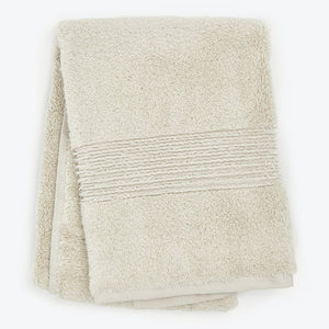 Neatly folded beige bath towel with decorative ribbed texture.