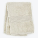 Neatly folded beige bath towel with decorative ribbed texture.