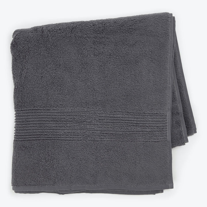 Plush charcoal gray bath towel with ribbed border on white.