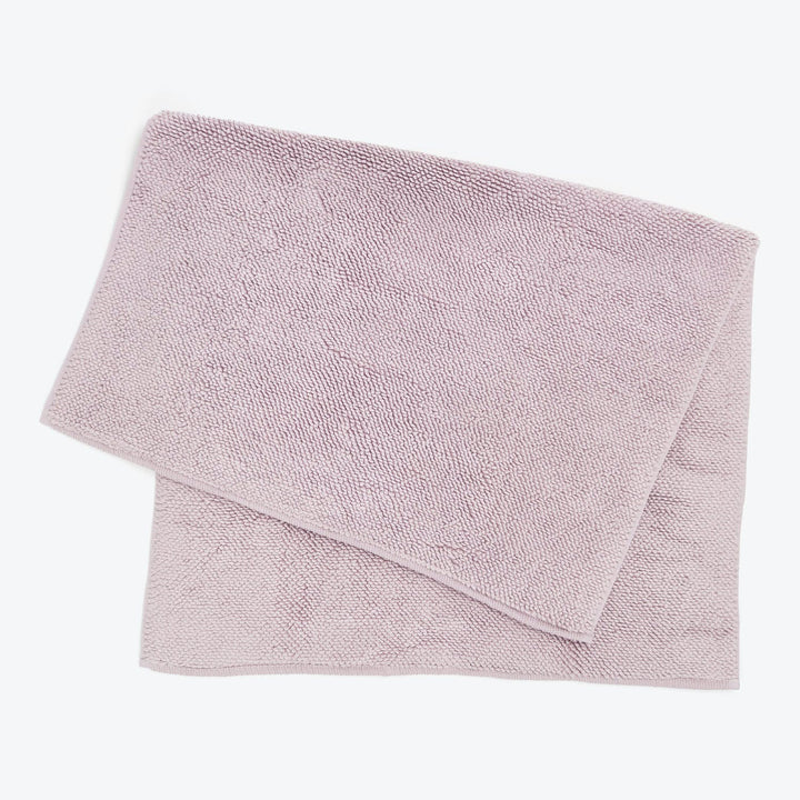 Soft pink terrycloth towel neatly folded on white background, clean.