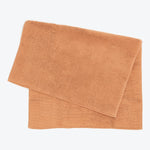 Two terracotta-colored terrycloth towels folded on white background.
