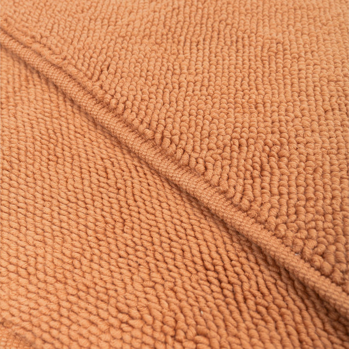 Close-up of plush, textured fabric in warm orange-brown color.