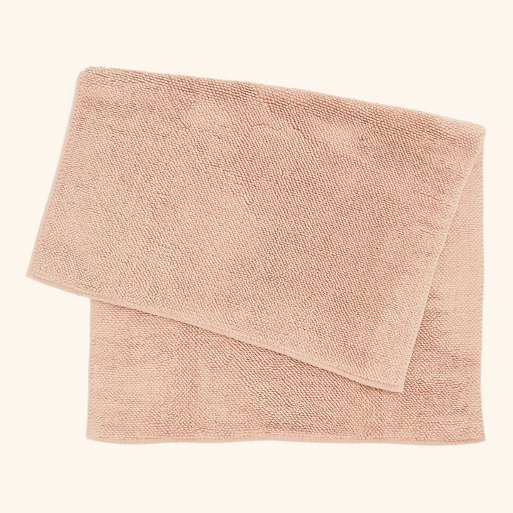 Soft, fluffy pale pink towel neatly folded on white background.