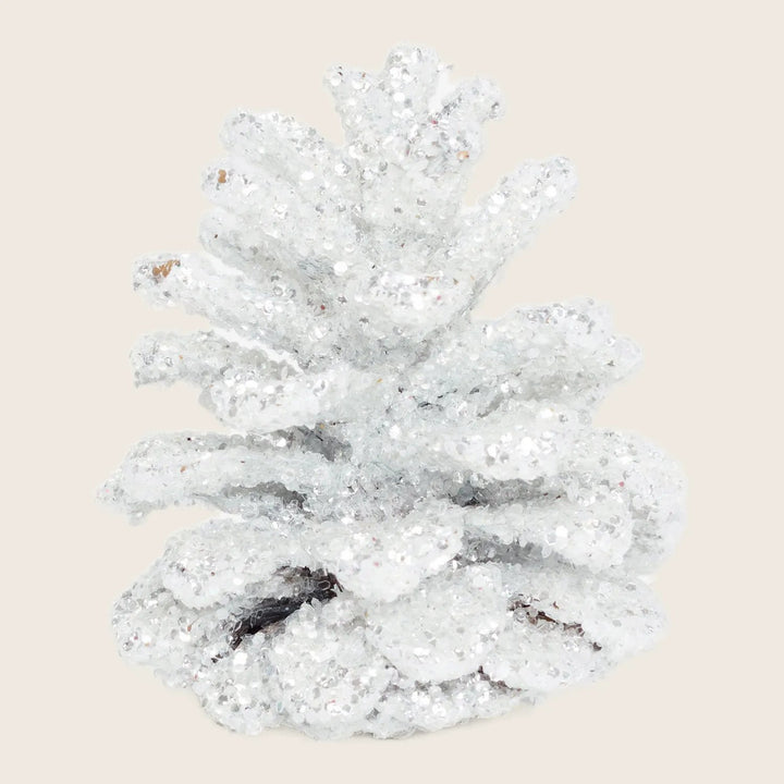 Glitter-coated pinecone sparkles in festive holiday decoration, white background.