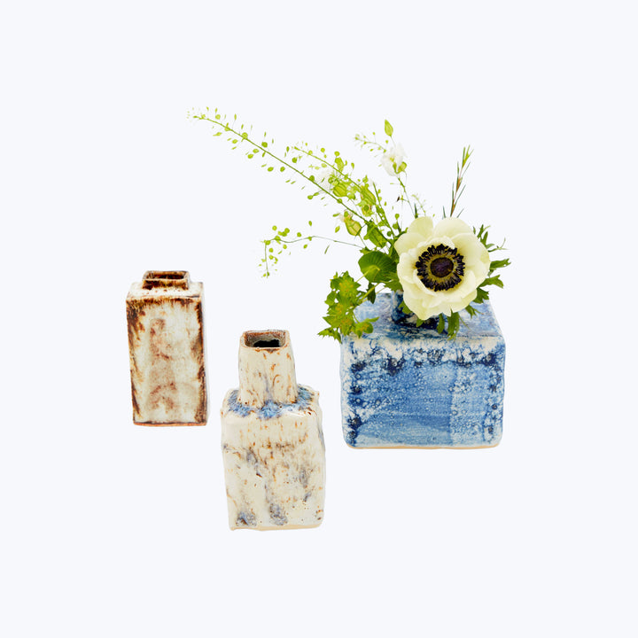 Rustic ceramic vases with floral arrangement against white background.