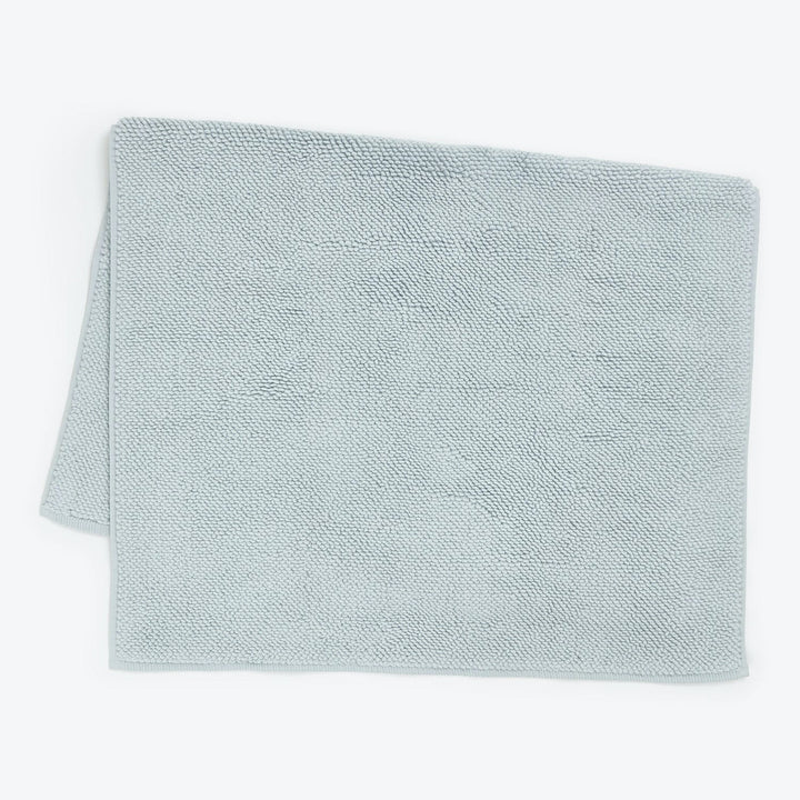 Neatly folded light blue towel on white background, soft fabric.