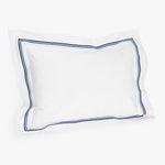 White pillow with blue piping trim on a soft background.