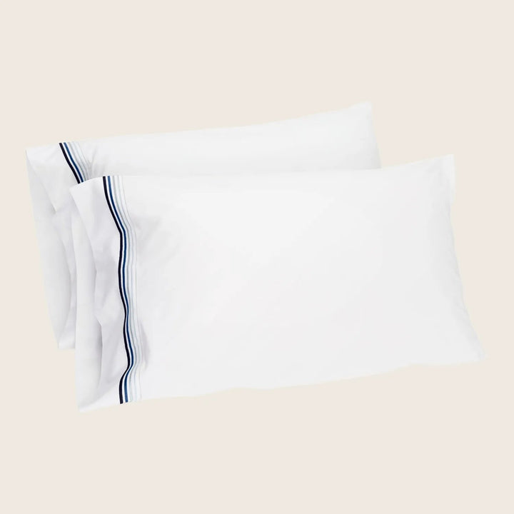 Crisp white pillowcases with navy blue stripe design, clean and fresh.