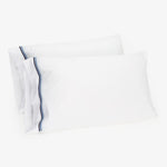 Crisp white pillowcases with navy blue stripe design, clean and fresh.