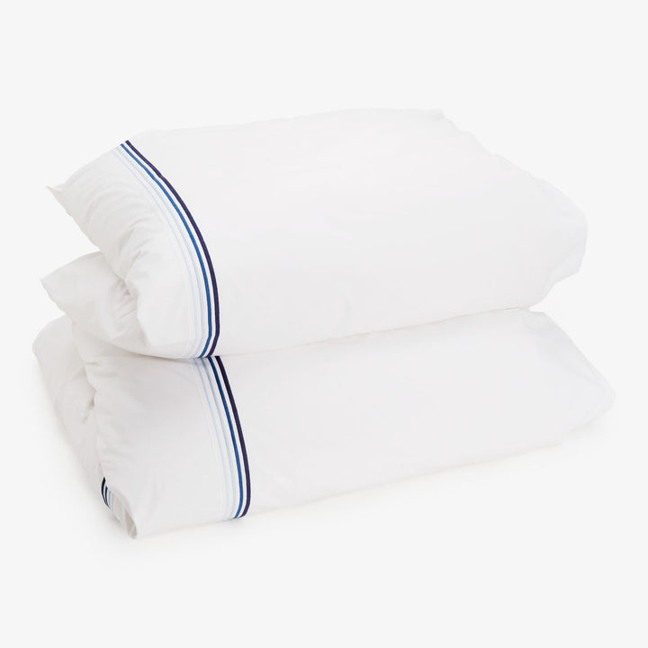 Two white pillows with navy and light blue trim stripes.