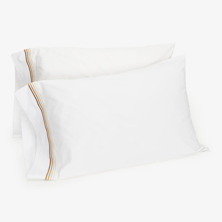 Decorative striped pillowcases in neutral tones on white background.