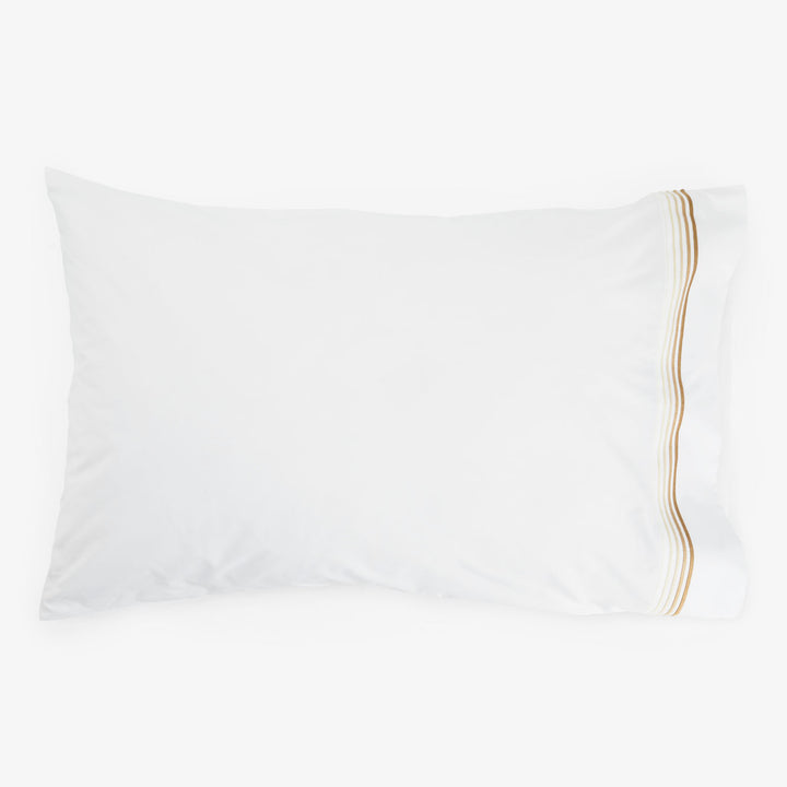 White pillow with gold striped accent on white background. Soft texture.