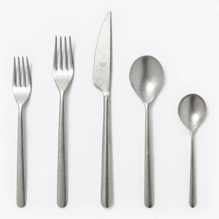 Modern set of five sleek cutlery pieces on light background.