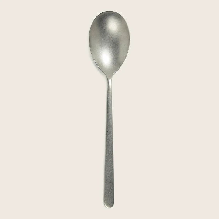 Minimalist stainless steel spoon with slight wear, isolated on white.