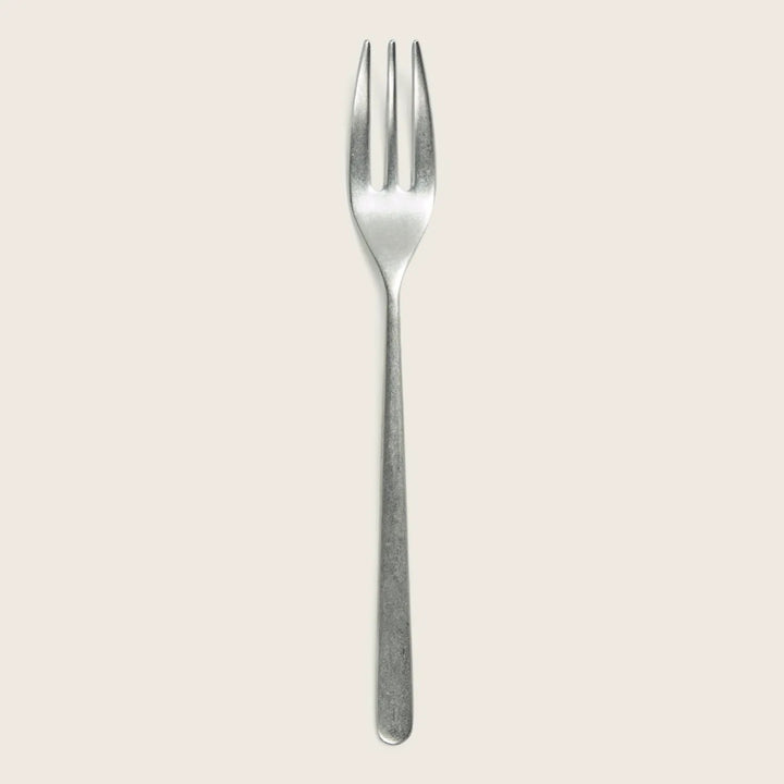 Single metal fork with four tines on white background close-up