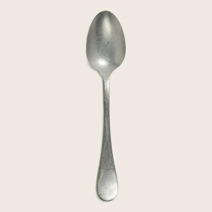 Simple metal spoon with wear, oval bowl, straight handle design.