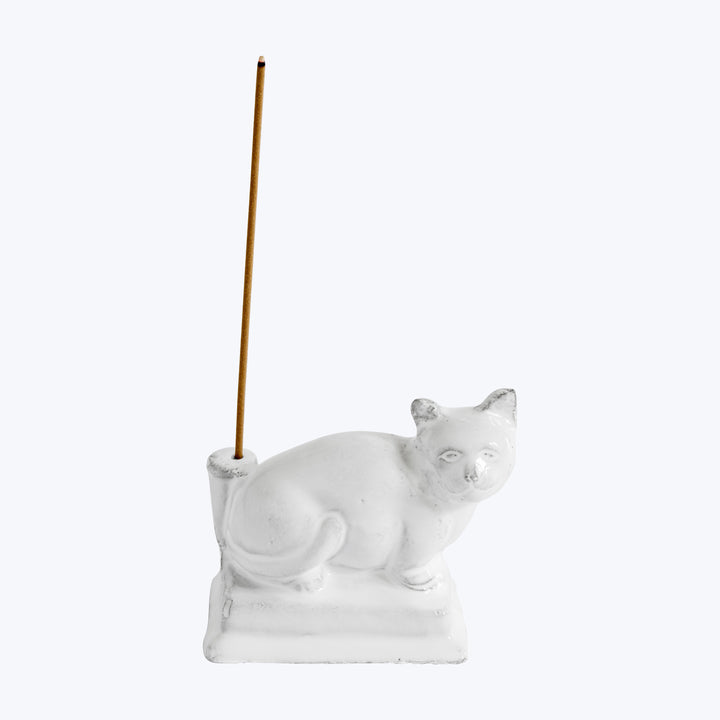 White cat-shaped incense holder with stylized features and incense stick