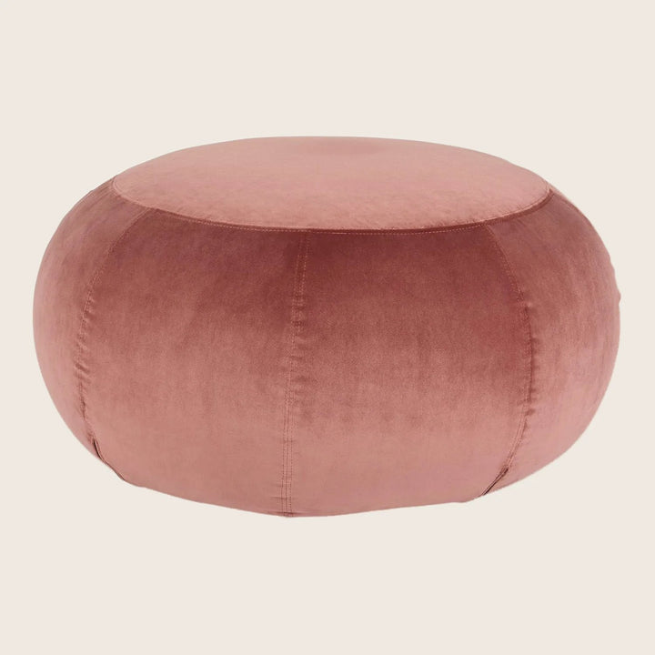 Round, blush-pink pouf with plush velvet texture and stitched segments.