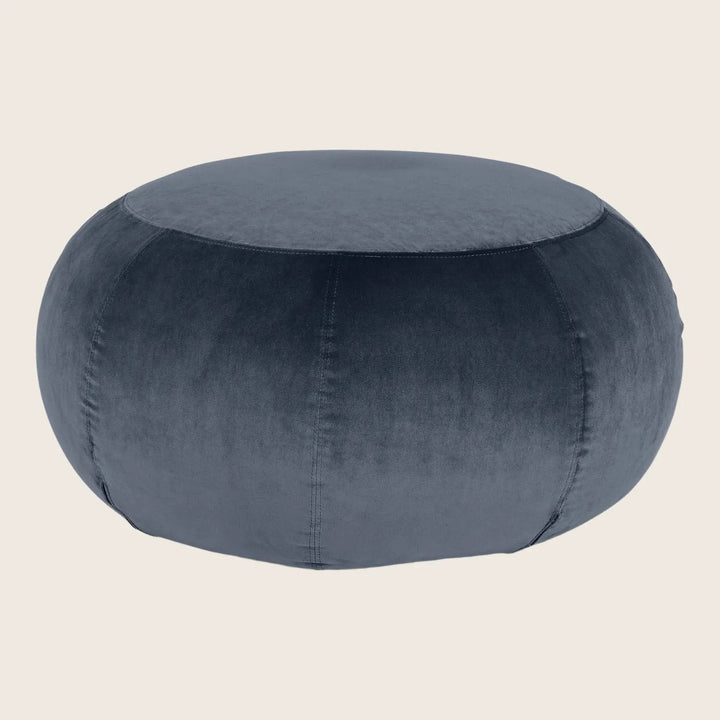 Dark gray velvet pouf with plush cushioned appearance and stitched seams