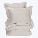 Neutral colored bedding set displayed in a stack, soft fabric