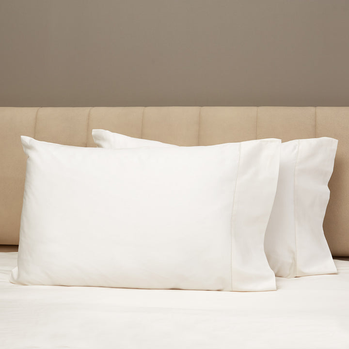 Minimalist bedroom with white pillows and beige upholstered headboard.