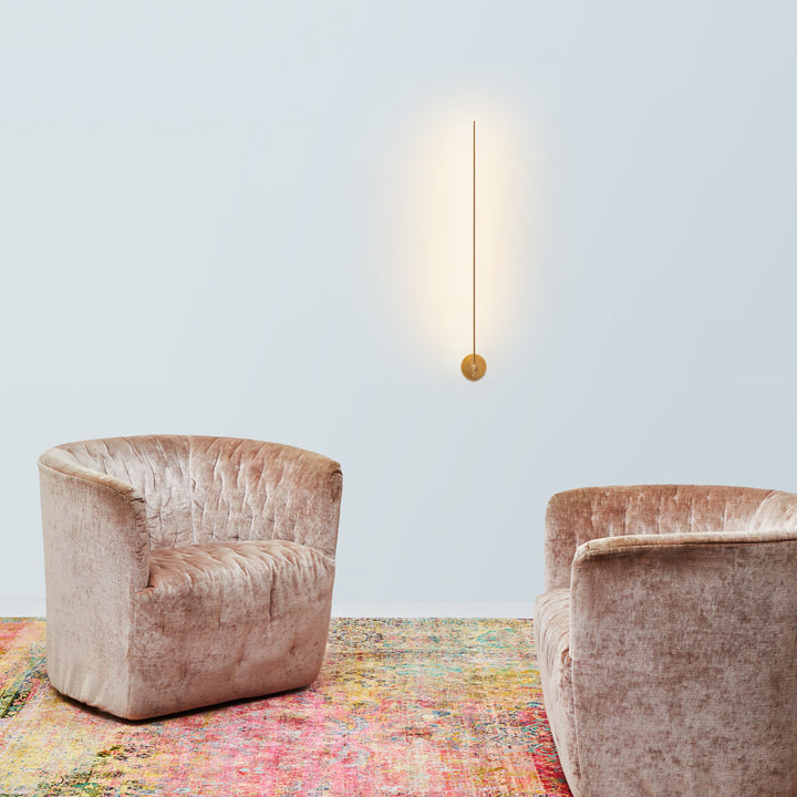 Modern interior with plush pink armchairs, colorful rug, and pendant light.