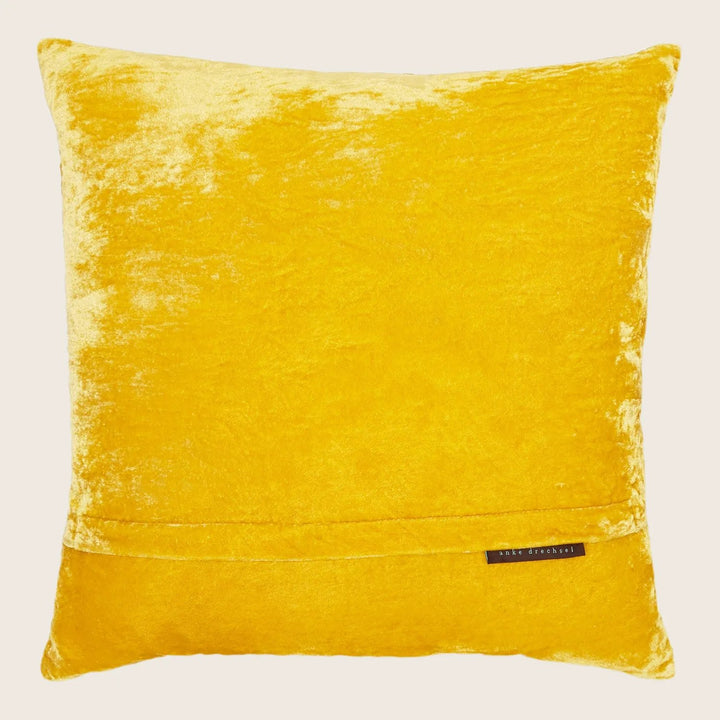 Vibrant yellow square pillow with soft velvet texture and label.