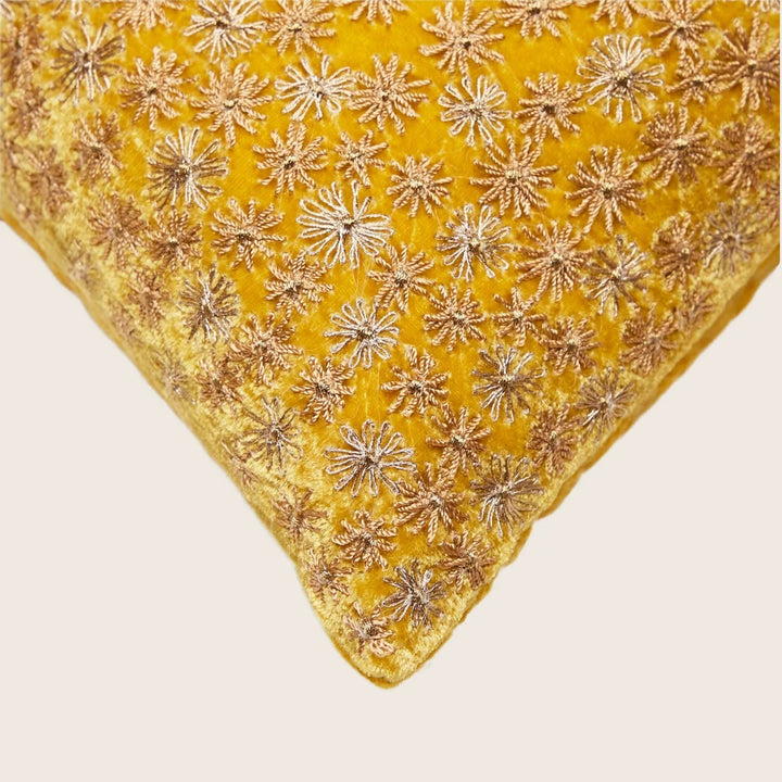 Luxurious golden cushion with intricate bronze embroidery on plush surface
