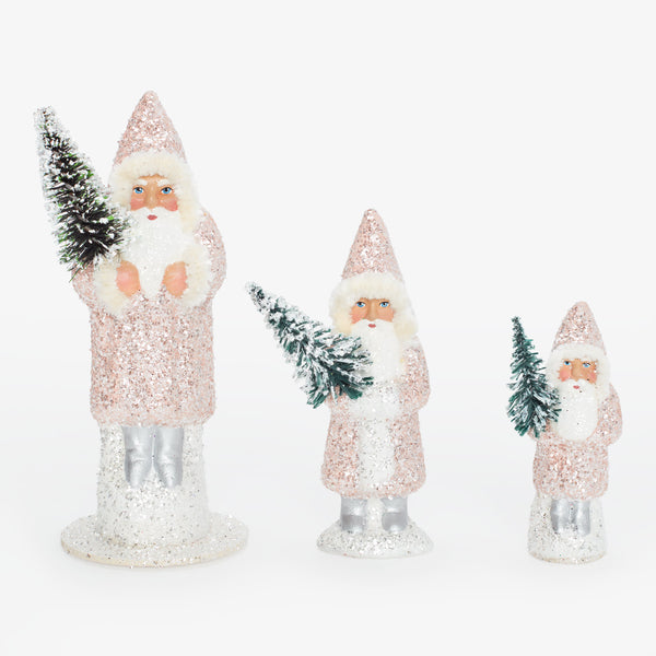 Three Santa Claus figurines in descending size, holding trees, glittered