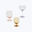 Three stemware glasses of different colors against white background.