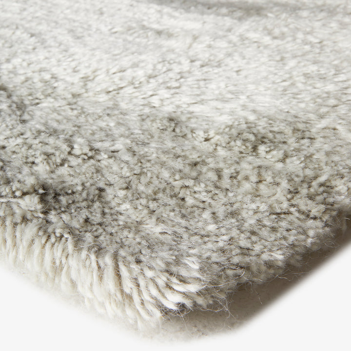 Close-up of fluffy white rug with plush pile fibers texture.