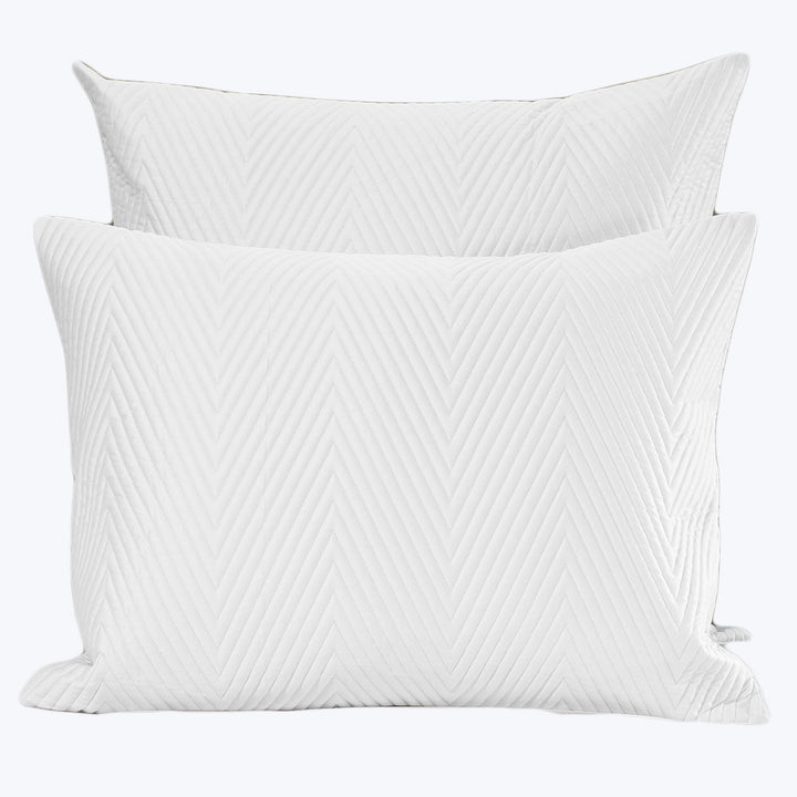 Two white herringbone quilted pillows on white background.