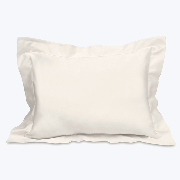 Smooth off-white pillowcase on plump pillow with decorative flange.