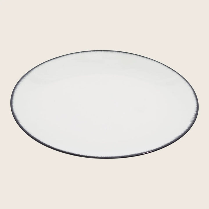 Minimalistic ceramic plate with white center and black trim edge.