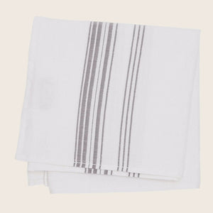 Neatly folded white towel with vertical stripe design in tan - hover