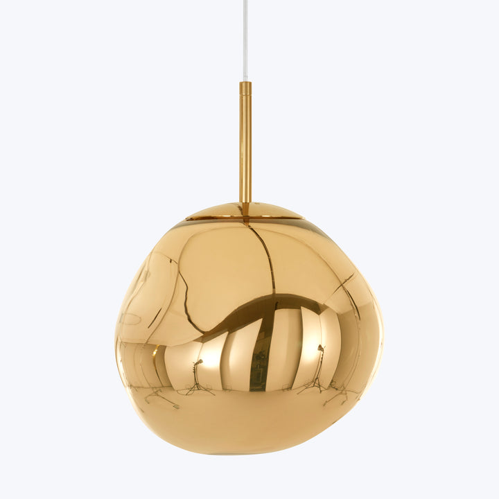 Golden pendant light with cracked surface suspended from ceiling cable.