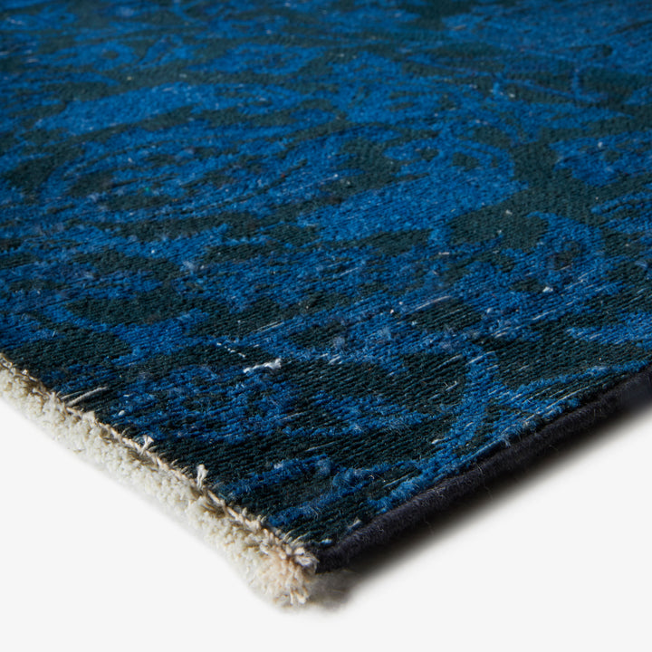Close-up of blue and gray rug corner, highlighting texture and edge.