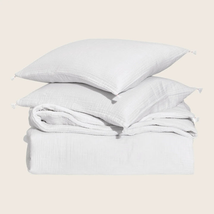 Neatly arranged white bed linen and pillows on display.