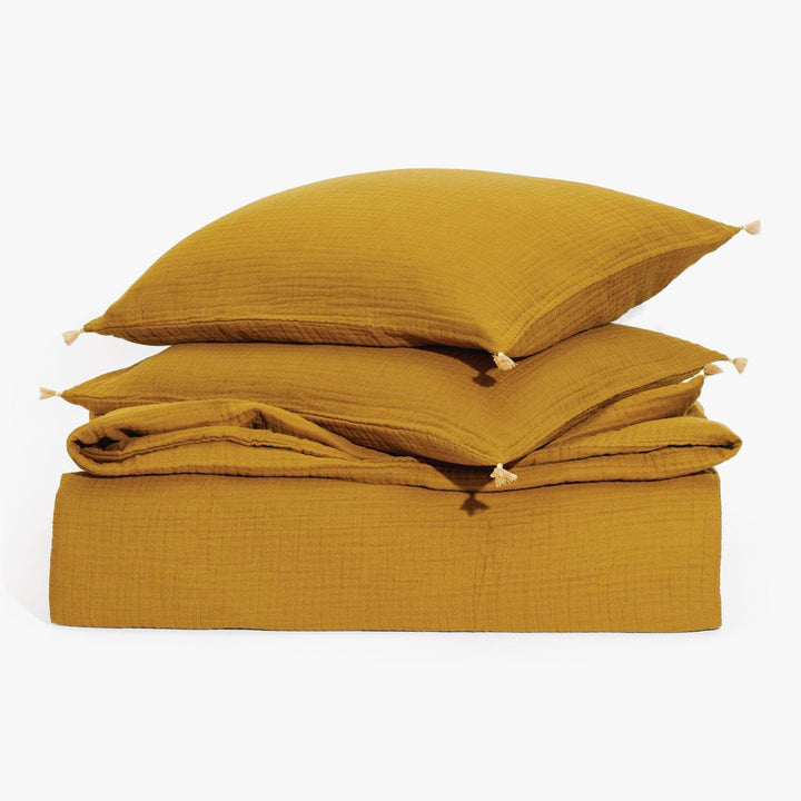 Cozy mustard yellow bedding with textured pillows and tassels.