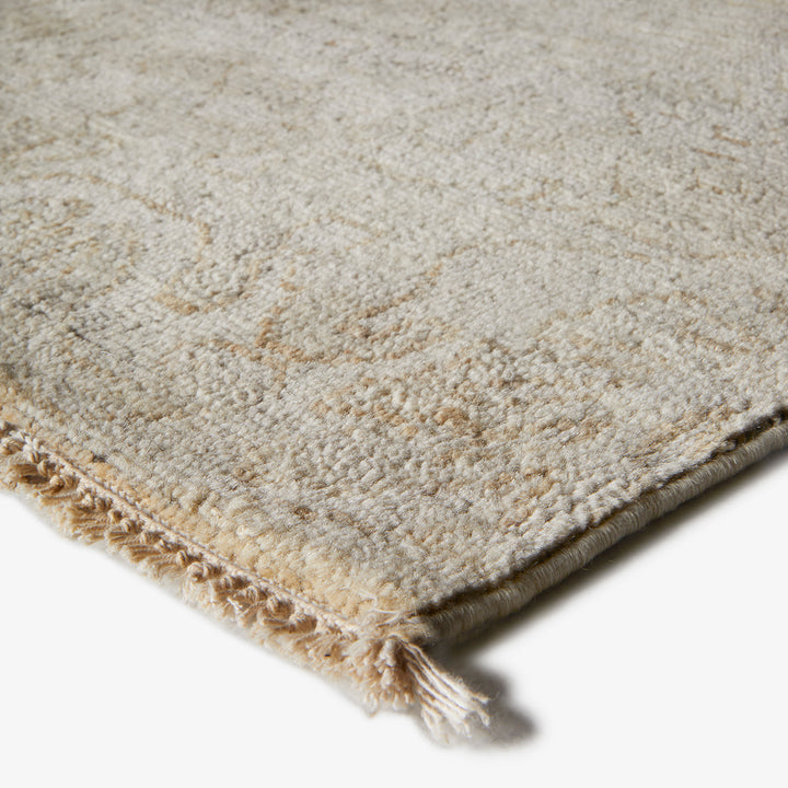 Neutral tone textured rug with looped pile fabric and fringe.