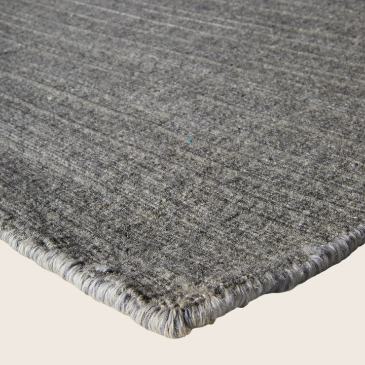 Close-up of gray textile carpet with ribbed texture and serging.