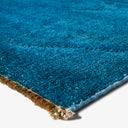 Close-up of blue carpet corner with dense soft pile texture.