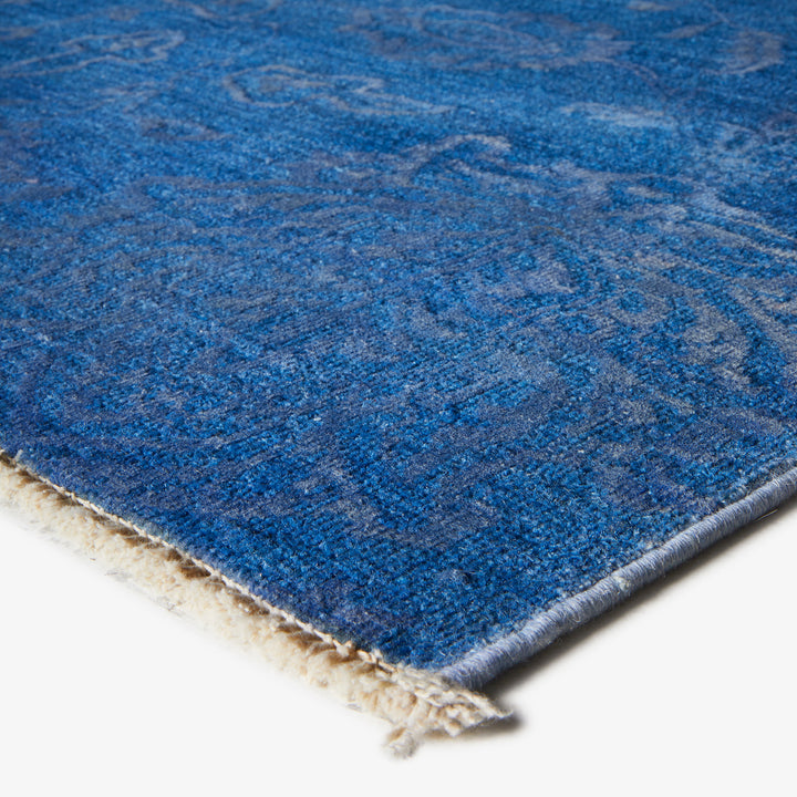 Close-up of blue patterned carpet corner with soft, dense texture.