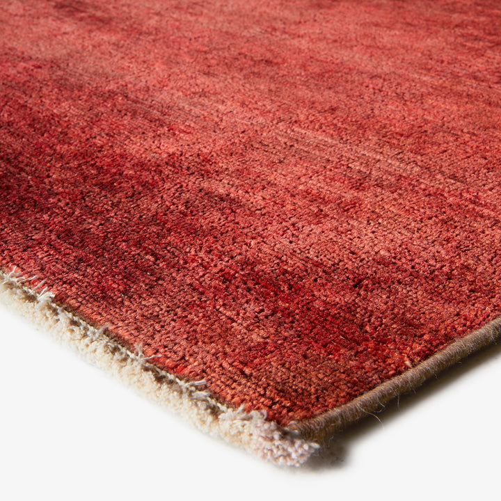 Close-up view of red textured rug with folded edge detail.