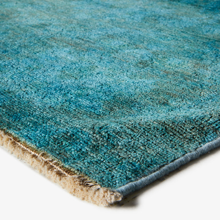 Close-up of dense, soft blue rug with beige woven backing.