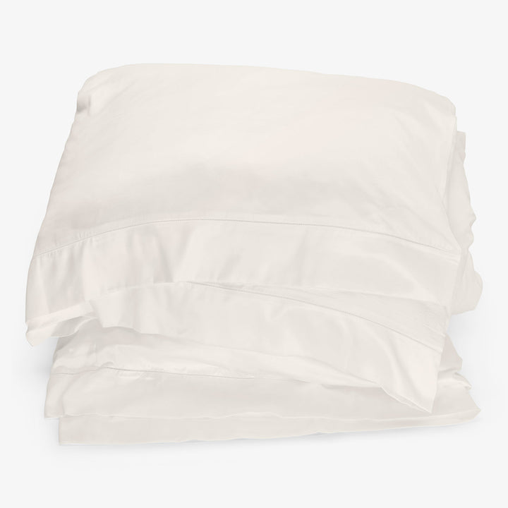 Crisp white bed linens folded neatly in classic style.