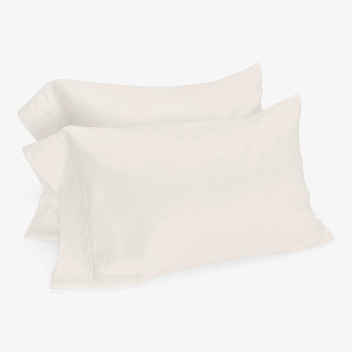 Two white pillowcases on stacked pillows against clean background.