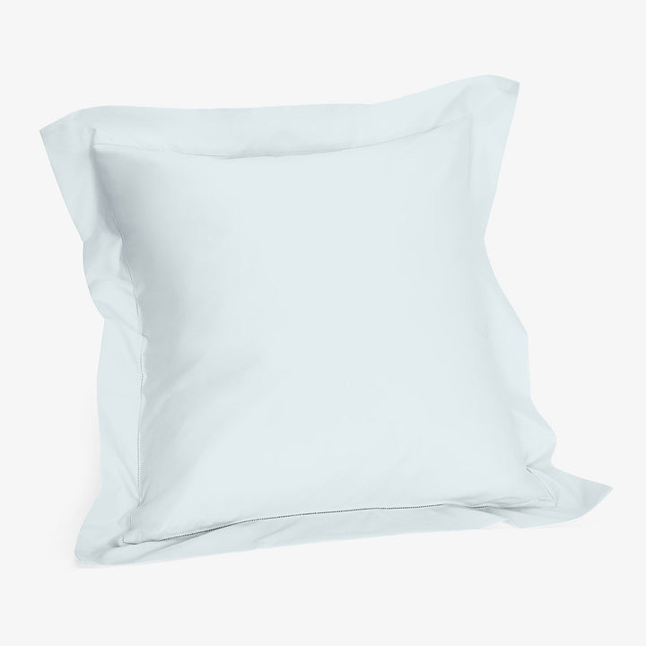 Plain white pillowcase with inner flap on smooth fabric surface.