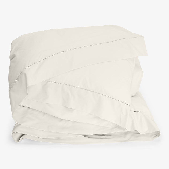 Off-white duvet cover set with pillowcase, neatly folded and stacked.