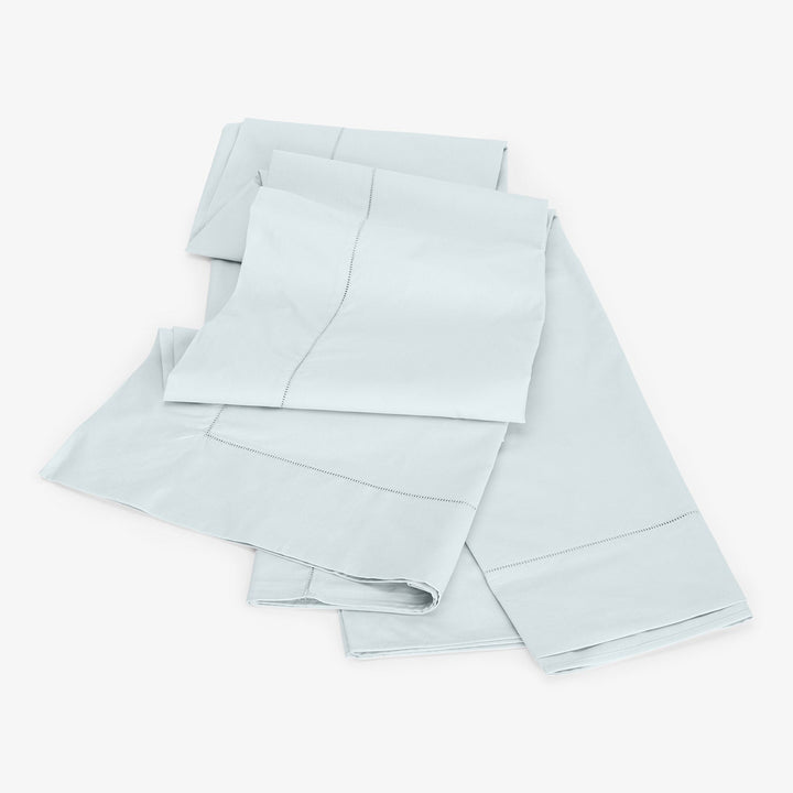 Neatly folded light blue sheets on light background, high-quality stitching.